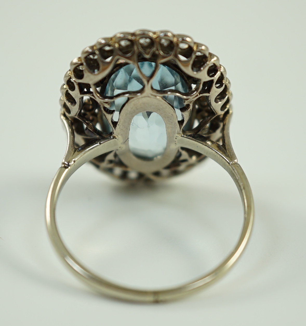 An 18ct white gold and single stone oval cut aquamarine set dress ring, with brilliant cut diamond set border